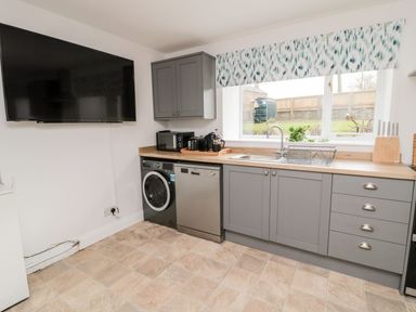 A utility room with a washing machine and a television at Whinney Moor