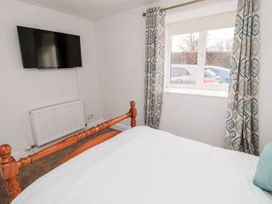 A bedroom with a bed and TV mounted on the wall at Whinney Moor