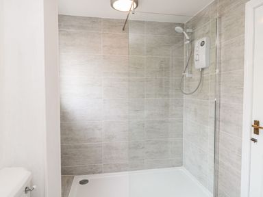 A shower area with tile walls and shower control unit at Whinney Moor in 