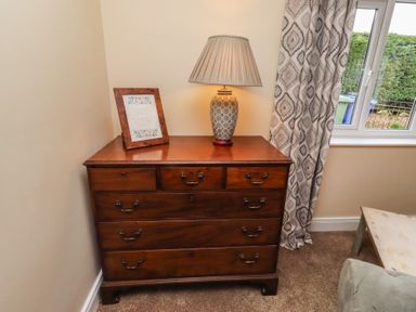 A living room with a wooden dresser and a lamp at Whinney Moor in Alnwick