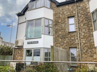 A building with stone and white walls with windows and a sign that says Four Seasons at 7 Four Seasons in Carbis Bay