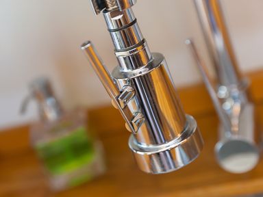 A close-up of a metallic faucet handle with a blurred soap dispenser in the background at 7 Four Seasons in Carbis Bay