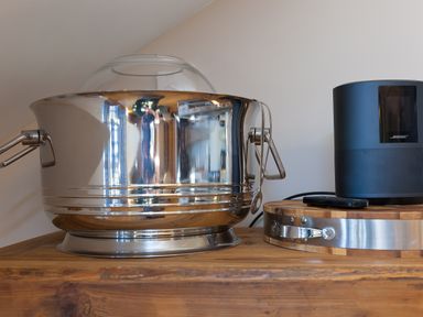 A metal ice bucket with a glass lid and a black Bose speaker on a wooden surface at 7 Four Seasons in Carbis Bay