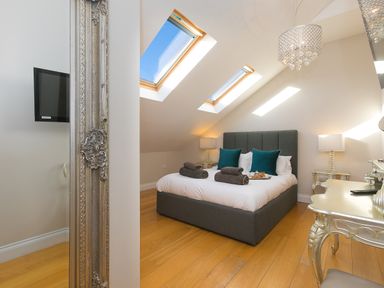 A bedroom with a double bed under skylights and decorative furniture at 7 Four Seasons in Carbis Bay