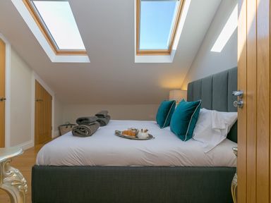 A bedroom with a double bed two skylight windows and folded towels at 7 Four Seasons in Carbis Bay