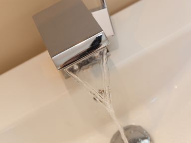 A modern square faucet with water flowing into a white sink at 7 Four Seasons in Carbis Bay