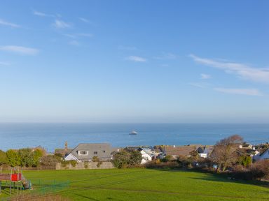 A view of houses near the sea with a boat on the water and a green field with a playground in the foreground at 7 Four Seasons in Carbis Bay