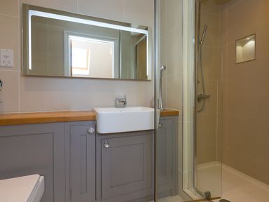 A bathroom with a sink and gray cabinets next to a glass shower at 7 Four Seasons in Carbis Bay