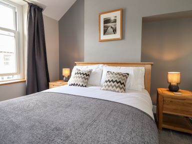 A bedroom with a double bed two bedside tables with lamps and a framed picture above the bed at Dovestones in Keswick