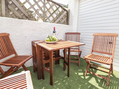 An outdoor patio area with wooden table and chairs on artificial grass at Dovestones Keswick
