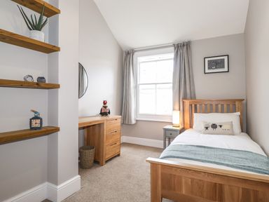 A bedroom with a wooden bed a desk with a stuffed bird and shelves on the wall at Dovestones in Keswick