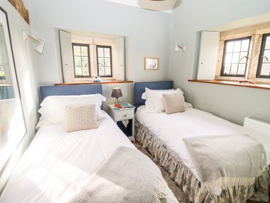 A bedroom with two single beds and a nightstand between them at The Small House Near Bourton-On-The-Water