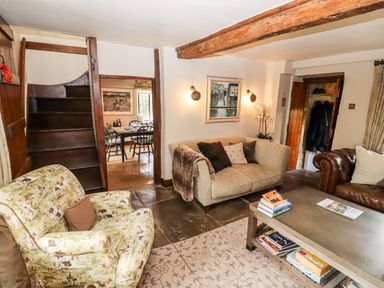 A living room with sofas a patterned armchair and a coffee table with books at The Small House Near Bourton-On-The-Water