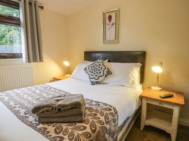 A bedroom with a made bed two bedside tables with lamps and a window at Bugle in Saltburn-By-The-Sea