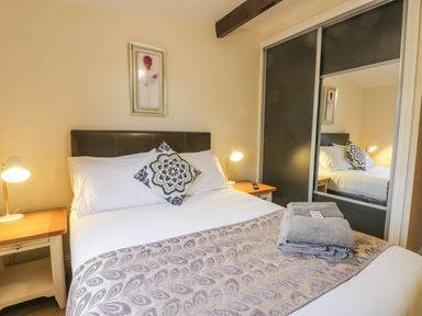 A bedroom with a bed with white bedding and patterned cushion a framed picture bedside tables with lamps and folded towels on the bed at Bugle in Saltburn-By-The-Sea