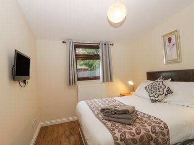 A bedroom with a double bed a wall-mounted television and a window with curtains at Bugle in Saltburn-By-The-Sea