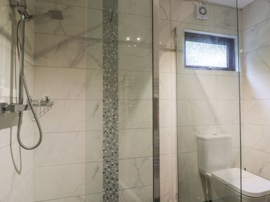 A bathroom with a walk-in shower and a toilet under a small window at Bugle in Saltburn-By-The-Sea