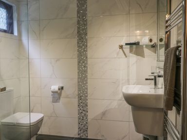 A bathroom with a toilet a sink a towel hanging a small window and tiled walls at Bugle in Saltburn-By-The-Sea