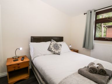 A bedroom with a double bed two bedside tables with lamps and a window with curtains at Lavender Lodge in Saltburn-By-The-Sea
