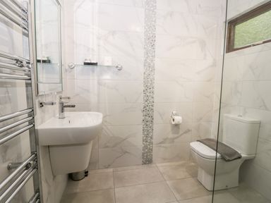 A bathroom with a sink toilet towel radiator and a glass shelf at Lavender Lodge in Saltburn-By-The-Sea
