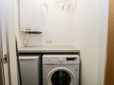 A laundry room with a washing machine a small refrigerator a countertop and a wall-mounted boiler at Lavender Lodge in Saltburn-By-The-Sea