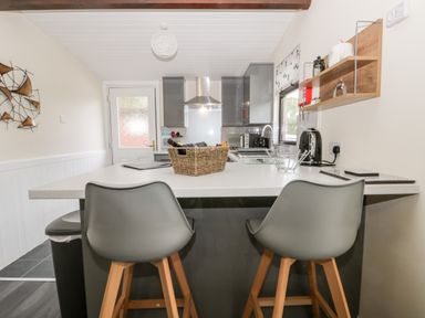 A kitchen with a white countertop island and two gray chairs at Lavender Lodge in Saltburn-By-The-Sea