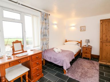 A bedroom with a single bed a wooden desk a chair and a wardrobe at Littleham Court Cottage in Littleham near Bideford