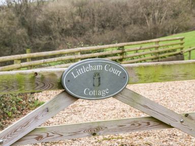 A wooden gate with a sign reading Littleham Court Cottage in a rural area at Littleham near Bideford