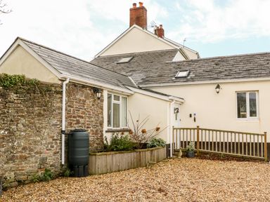 Exterior view of a house with stone and cream walls a gravel driveway and plants in a wooden planter at Littleham Court Cottage Littleham near Bideford
