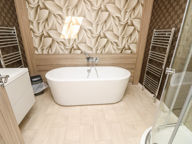 A bathroom with a freestanding bathtub a shower cabinet and towel warmers at Crosswinds 67 Bembridge