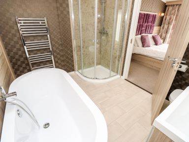 A bathroom with a bathtub shower enclosure towel rail and a view into a bedroom at Crosswinds 67 in Bembridge