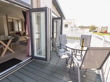 A balcony with a round table and four chairs overlooking a residential area at Crosswinds 67 in Bembridge