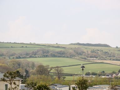 A countryside view with fields hills and houses in the foreground at Crosswinds 67 in Bembridge