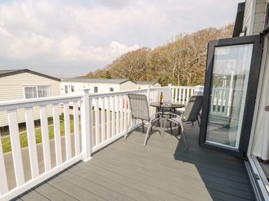 A balcony with a round table and two chairs overlooking a mobile home park at Crosswinds 67 in Bembridge