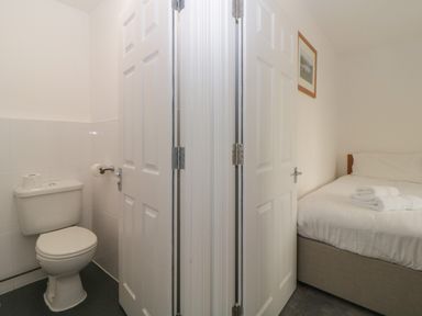 A bathroom with a toilet and a bedroom with a bed and folded towels at Harcombe House Bungalow 3 in Chudleigh
