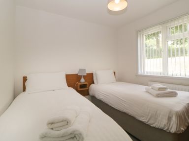 A bedroom with two single beds a bedside lamp and window blinds at Harcombe House  Bungalow 4 in Chudleigh