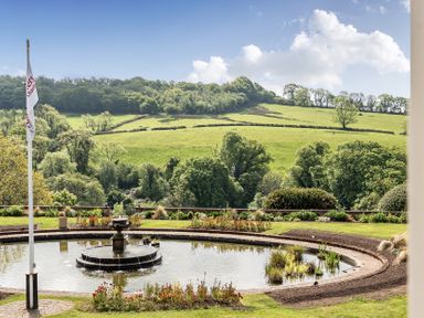 A garden with a fountain and plants at Harcombe House Pet Free Bungalow in Chudleigh