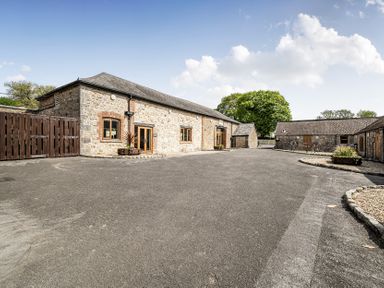 An outdoor view of a stone building with parking area at Harcombe House Pet Free Bungalow Chudleigh