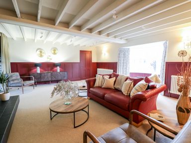 A living room with a red sofa and wooden coffee tables at Dant Y Llew in Bow Street Wales