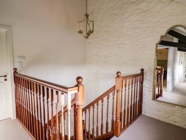 A stairway with wooden railings and a large mirror on a stone wall at Dant Y Llew in Bow Street Wales