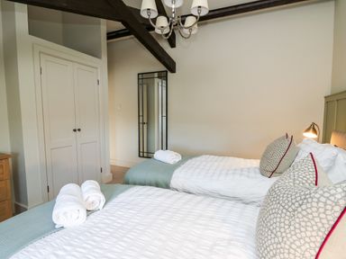 A bedroom with two beds white linens rolled towels and patterned pillows at Dant Y Llew in Bow Street Wales
