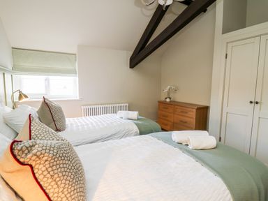 A bedroom with two single beds green blankets and pillows wooden dresser and closet doors at Dant Y Llew in Bow Street Wales