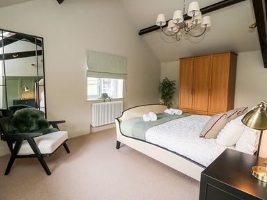 A bedroom with a bed sofa chair wardrobe and window at Dant Y Llew in Bow Street Wales