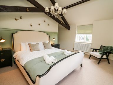 A bedroom with a bed two nightstands a chair and a window at Dant Y Llew in Bow Street Wales