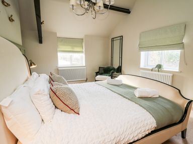 A bedroom with a bed two windows a chair and a mirror at Dant Y Llew in Bow Street Wales