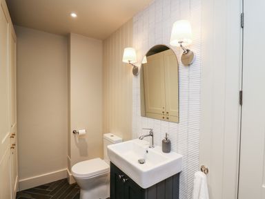 A bathroom with a toilet a sink a mirror and wall lamps at Dant Y Llew in Bow Street Wales