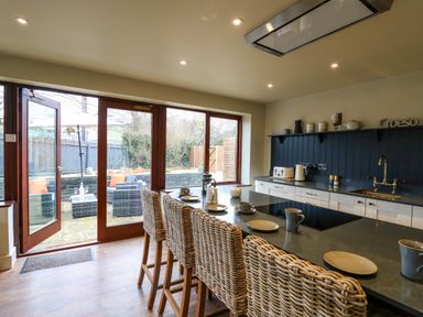 A kitchen with wicker bar stools and dinnerware on the island at Dant Y Llew in Bow Street Wales