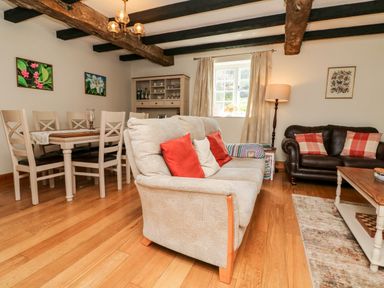 A living room with sofas a dining table wooden floor and ceiling beams at Home Farm Cottage in Fremington Devon