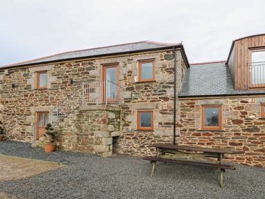 Stone building with multiple windows outdoor staircase and wooden picnic table at Pol View in Gunwalloe near Helston