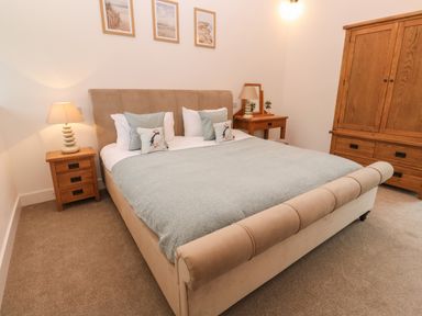 A bedroom with a bed side tables and wooden wardrobe at Pol View Gunwalloe near Helston